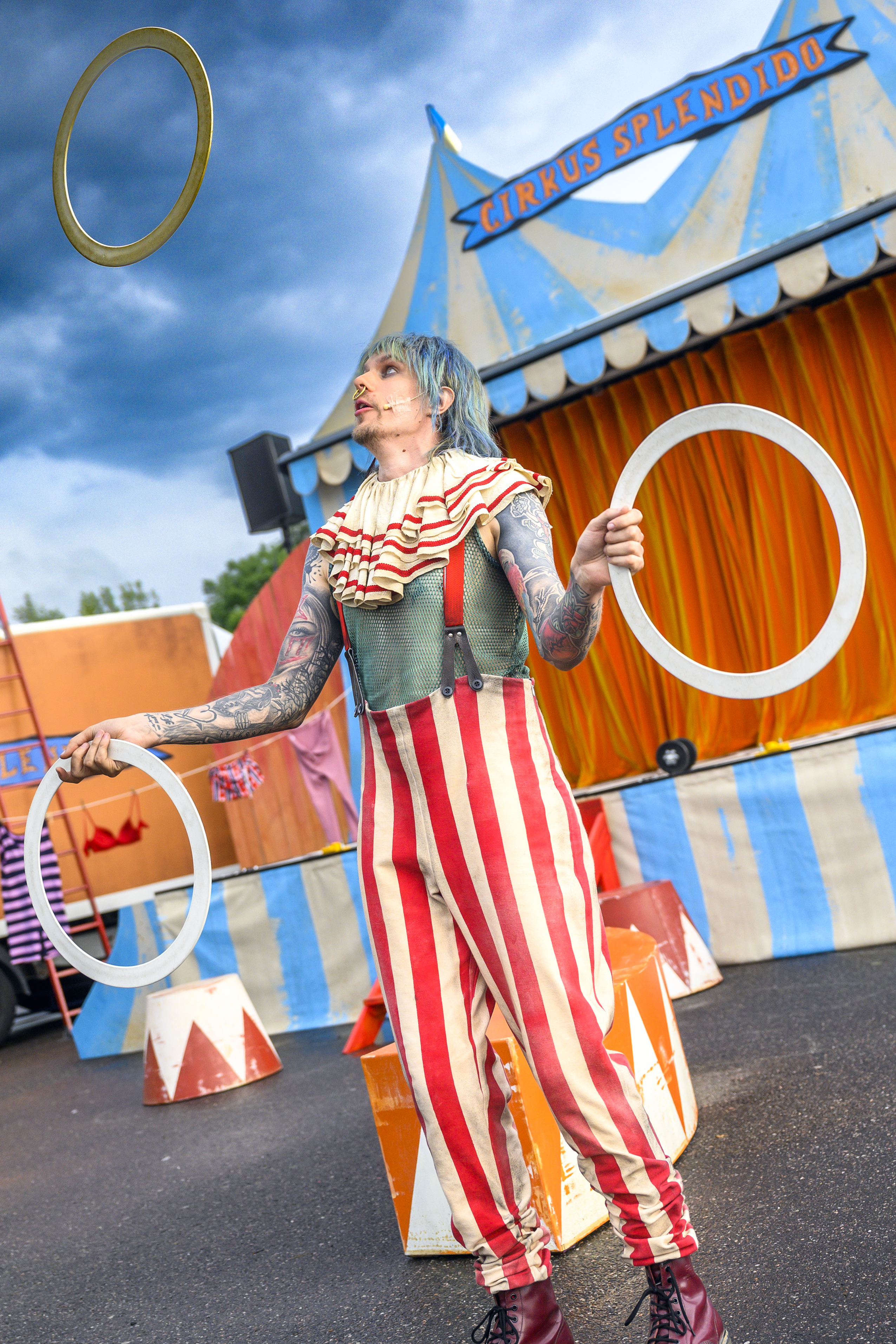 Cirkusartist i färgglada kläder jonglerar med ringar